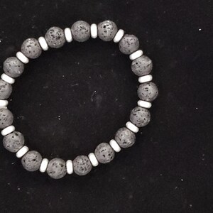 May include: A black lava rock bracelet with white spacer beads.