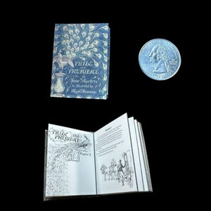 May include: Miniature book of "Pride and Prejudice" by Jane Austen, illustrated by Hugh Thomson, with a blue cover featuring a peacock design. The book is open, revealing interior illustrations. A US quarter is next to the book.