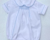 Baby boy's white smocked summer romper with pale blue piping. Available from birth to 18 months