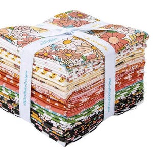 May include: A stack of floral fabric squares in various colors, including orange, yellow, and black, tied with a white ribbon. The fabric features a daisy pattern. The ribbon has the text "Riley Blake Designs".