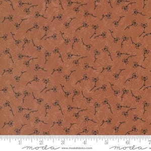 May include: A brown fabric with a repeating pattern of small black stylized flowers. The fabric has a slightly textured surface.