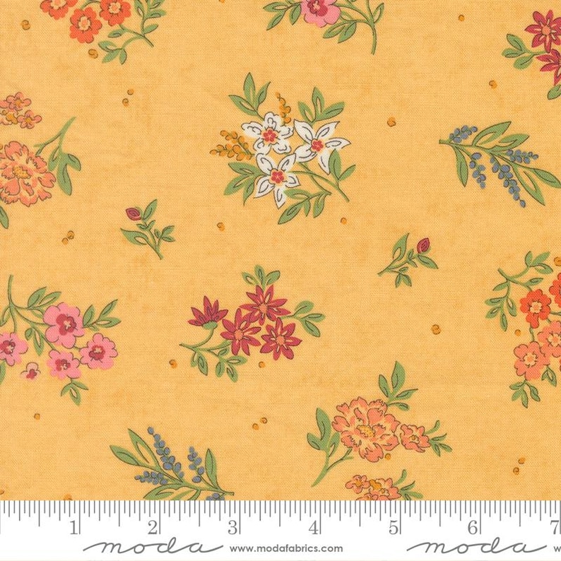 May include: A golden yellow fabric featuring a repeating floral pattern with clusters of small flowers in shades of pink, orange, red, and white, accented by green leaves and stems, with a white ruler showing 7 inches at the bottom edge.