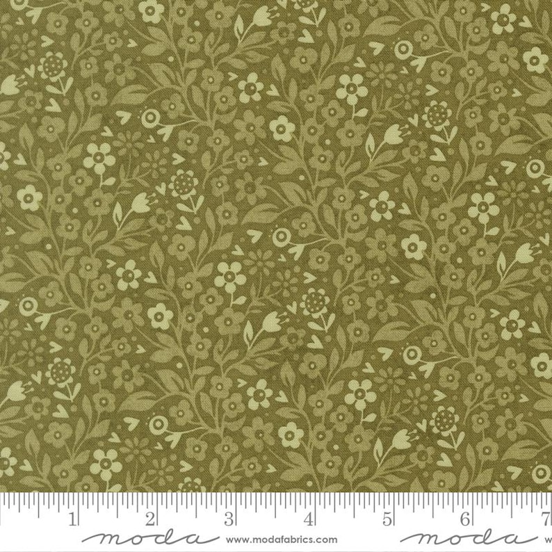 May include: A fabric swatch featuring an olive green background with a dense, repeating pattern of small, light cream-colored flowers and leafy vines. A white ruler at the bottom shows measurements in inches, ranging from 0 to 7 inches.