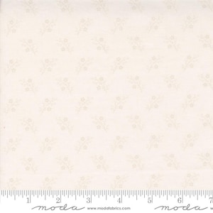 May include: Cream-colored fabric with a repeating pattern of small, light brown floral sprigs. The fabric has a subtle texture and a ruler is visible along the bottom edge, with the brand name "moda" printed on it.