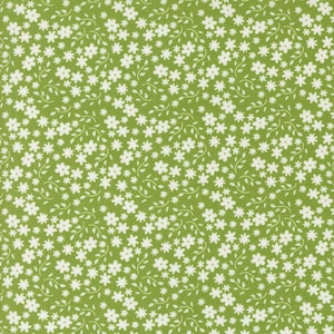 May include: A green fabric with a white floral pattern. The flowers are small and scattered throughout the fabric.