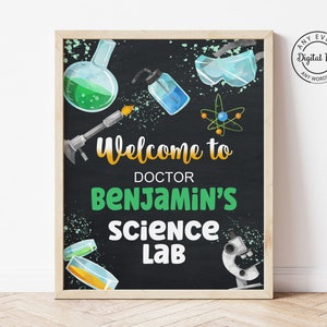 Puede incluir: Un cartel de pizarra con fondo negro y escritura en tiza blanca. El cartel dice "Bienvenido al laboratorio de ciencias del doctor Benjamin". El cartel está decorado con imágenes de vasos de precipitados, tubos de ensayo, gafas de seguridad y un microscopio.