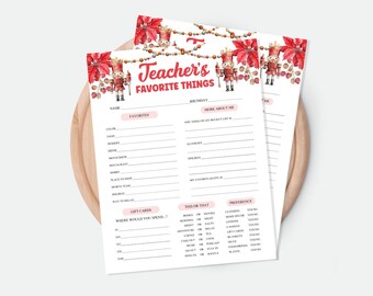 May include: Two white sheets of paper with the text "Teacher's Favorite Things" in red and gold. The top of the sheets are decorated with red poinsettias and toy soldier illustrations. The sheets are on a wooden surface.