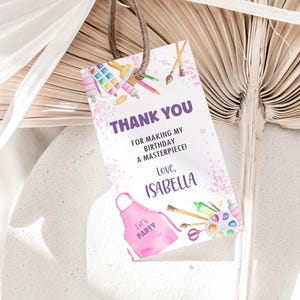 Puede incluir: Gracias por hacer de mi cumpleaños una obra maestra! Con cariño, Isabella. Una etiqueta de agradecimiento de temática artística rosa y morada con pinceles, tubos de pintura y una paleta de pintura.