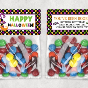 May include: Two clear cellophane bags filled with colorful candies. Each bag has a decorative topper with Halloween-themed text and graphics. One says "Happy Halloween!" and the other says "You've Been Booed!"