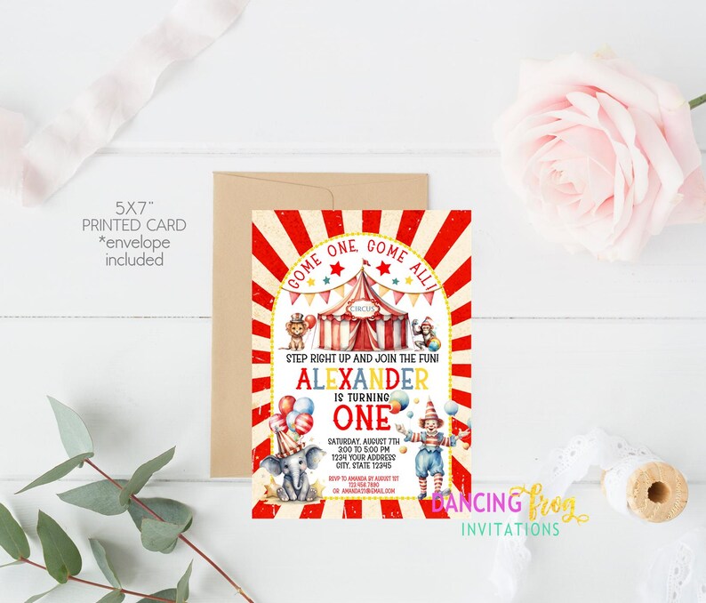 May include: A red and white striped circus tent with a yellow star and the words "Come One Come All" on the front. The tent is surrounded by colorful balloons and a clown holding a red and white striped ball. The text "Alexander is turning one" is printed in yellow and black letters. The invitation is for a birthday party on Saturday, August 7th from 2:00 to 5:00 PM. The address is 1234 Your Address, City, State 12345.