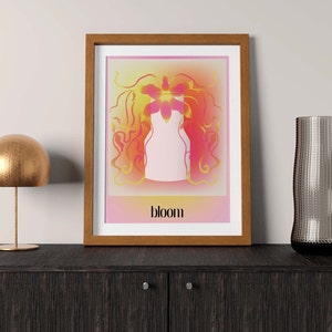 May include: A framed art print featuring a central white vase silhouette surrounded by abstract, flowing orange and pink floral shapes against a gradient background. The word bloom is printed in black, lowercase, sans-serif text at the bottom.