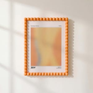 May include: A rectangular wall art print in a peach-colored beaded frame. The print features a soft, blurred gradient of yellow and orange hues. Text at the top reads Nostalgia Series 1970s, and text at the bottom reads JOY Gallery Exhibition.
