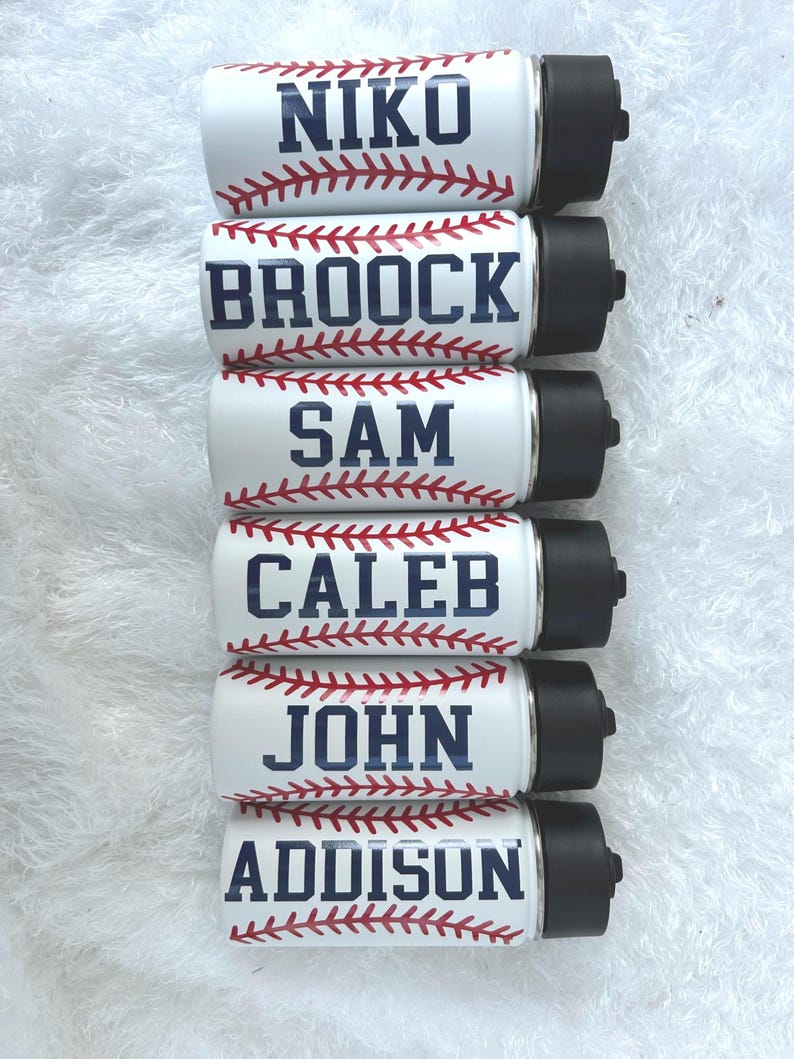 May include: Six white insulated water bottles with black lids, each featuring a baseball design. The names "NIKO", "BROOCK", "SAM", "CALEB", "JOHN", and "ADDISON" are printed in navy blue, with red baseball stitching.