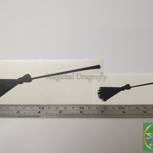May include: Two black silhouette witch broomstick decals on a white background. The larger broom is 17.8 cm long and the smaller broom is 10.2 cm long. The decals are shown next to a ruler for size comparison.
