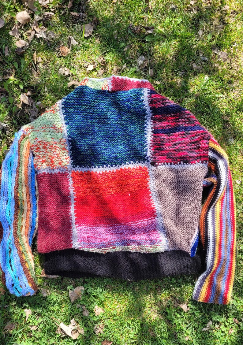 May include: A colourful patchwork knit sweater with long sleeves. The sweater is made of different coloured yarns and has a unique, handmade look.