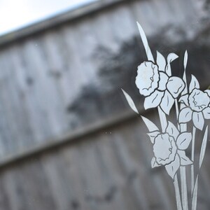 May include: A vintage mirror with an etched design of white flowers on a clear glass surface.