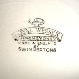Puede incluir: Primer plano de un plato de cer&aacute;mica blanco con un logotipo en blanco y negro que dice "Royal Wessex Ironstone Made in England by Swinnertons".