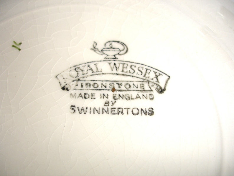 Puede incluir: Primer plano de un plato de cer&aacute;mica blanco con un logotipo en blanco y negro que dice "Royal Wessex Ironstone Made in England by Swinnertons".