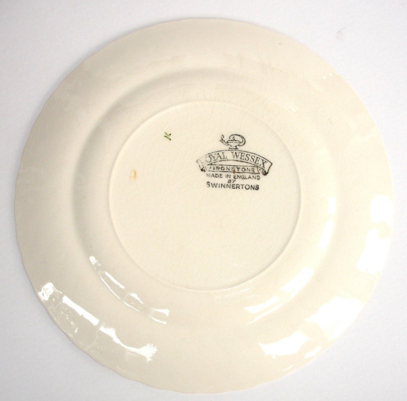Puede incluir: Plato de cer&aacute;mica blanco con un logotipo Royal Wessex Ironstone verde y negro. El logotipo dice "Royal Wessex Ironstone Made in England by Swinnertons".