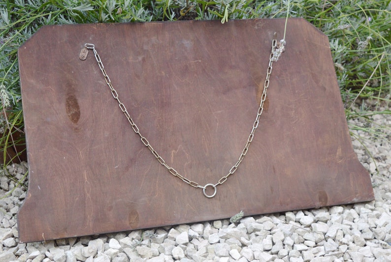 May include: The back of a wooden framed mirror with a metal chain and a ring hanging from it.
