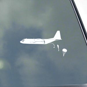 May include: White decal of a military cargo plane with two figures parachuting and a parachute. The plane is depicted in profile, with detailed features. The figures and parachute are below the plane.