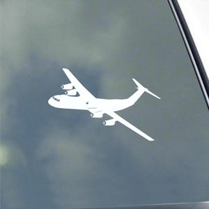 May include: White airplane decal featuring a detailed silhouette of a cargo plane. The decal shows the plane's wings, tail, and multiple engines. The design is clean and simple, suitable for various applications.