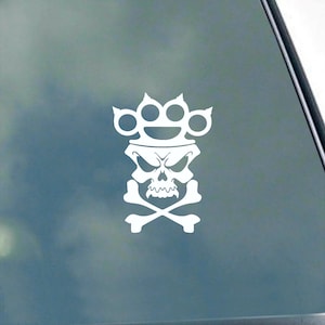 May include: White vinyl decal of a skull with a knuckle duster on its head and crossed bones below.