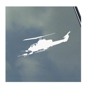May include: White silhouette of a helicopter with a long tail and two small missiles on the side. The helicopter is flying against a light blue cloudy sky.