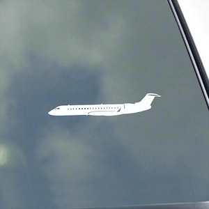 May include: A white airplane silhouette against a gray background. The plane has a long fuselage, wings, and a tail. The image is a simple, clean design, likely a decal or sticker.