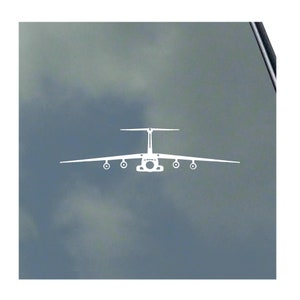 May include: A white silhouette of a large cargo plane against a blue cloudy sky. The plane is facing the viewer with its wings spread out.