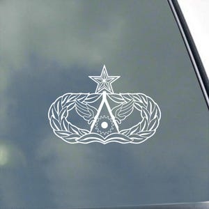 May include: White vinyl decal of an Air Force Space Command emblem. The emblem features a star, wings, and a gear.