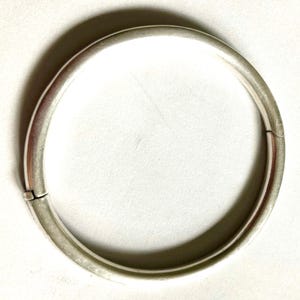 May include: A silver bangle bracelet with a hinged opening.