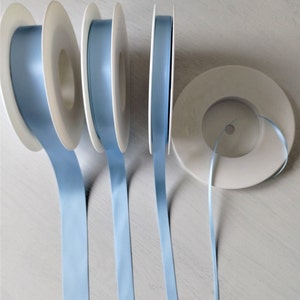 May include: Four spools of light blue satin ribbon, each wound around a white plastic spool.