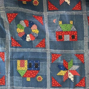 Può includere: Una trapunta blu a patchwork con vari motivi geometrici colorati, tra cui un fiore, una casa e una stella. La trapunta è realizzata con diversi tessuti e texture, creando un design unico e interessante.