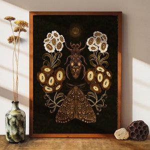 Può includere: Una stampa artistica incorniciata con un'illustrazione dettagliata di uno scarabeo, una falena e fiori stilizzati nei toni del marrone, crema e oro su uno sfondo scuro. L'opera d'arte è esposta su una superficie di legno.