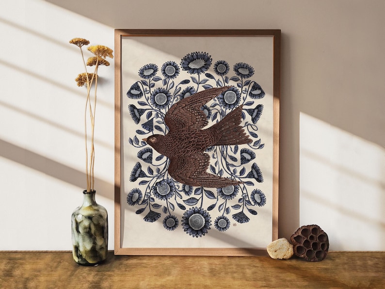 K&ouml;nnte beinhalten: Ein gerahmter Druck mit einem braunen Vogel mit blauen und wei&szlig;en floralen Details. Der Vogel ist im Flug dargestellt, mit ausgebreiteten Fl&uuml;geln. Das florale Design ist aufwendig und detailliert.