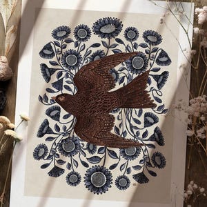 K&ouml;nnte beinhalten: Ein brauner Vogel mit ausgebreiteten Fl&uuml;geln, der durch einen Kreis aus blauen und wei&szlig;en Blumen fliegt. Der Vogel ist mit komplizierten Mustern verziert und die Blumen haben einen Vintage-Stil.