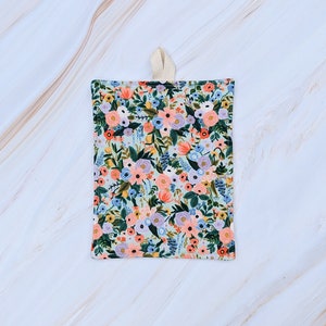 May include: A small, floral patterned kitchen towel with a cream-colored loop handle. The towel features a variety of flowers in shades of pink, blue, and yellow on a light blue background.