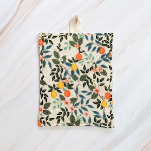 May include: A beige kitchen pot holder with a floral pattern featuring orange citrus fruit, green leaves, and white flowers.