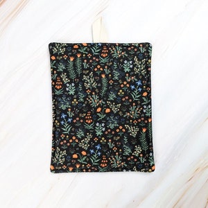 May include: A black pot holder with a floral pattern featuring orange, blue, and green flowers on a black background.