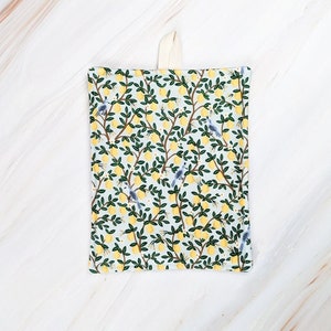 May include: A white fabric kitchen dishcloth with a lemon and bird print. The dishcloth has a loop for hanging.