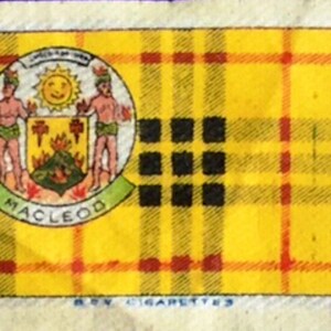 Könnte beinhalten: Ein gelbes und rotes Karomuster mit einem schwarzen und weißen Wappen in der Mitte. Das Wappen zeigt zwei Figuren, eine Sonne und das Wort "MacLeod". Der Text "ROY CIGARETTES" ist unter dem Karomuster gedruckt.