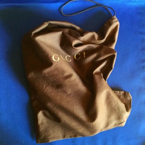 May include: A brown fabric dust bag with a gold Gucci logo.