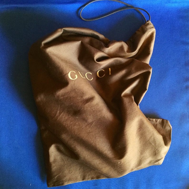 May include: A brown fabric dust bag with a gold Gucci logo.