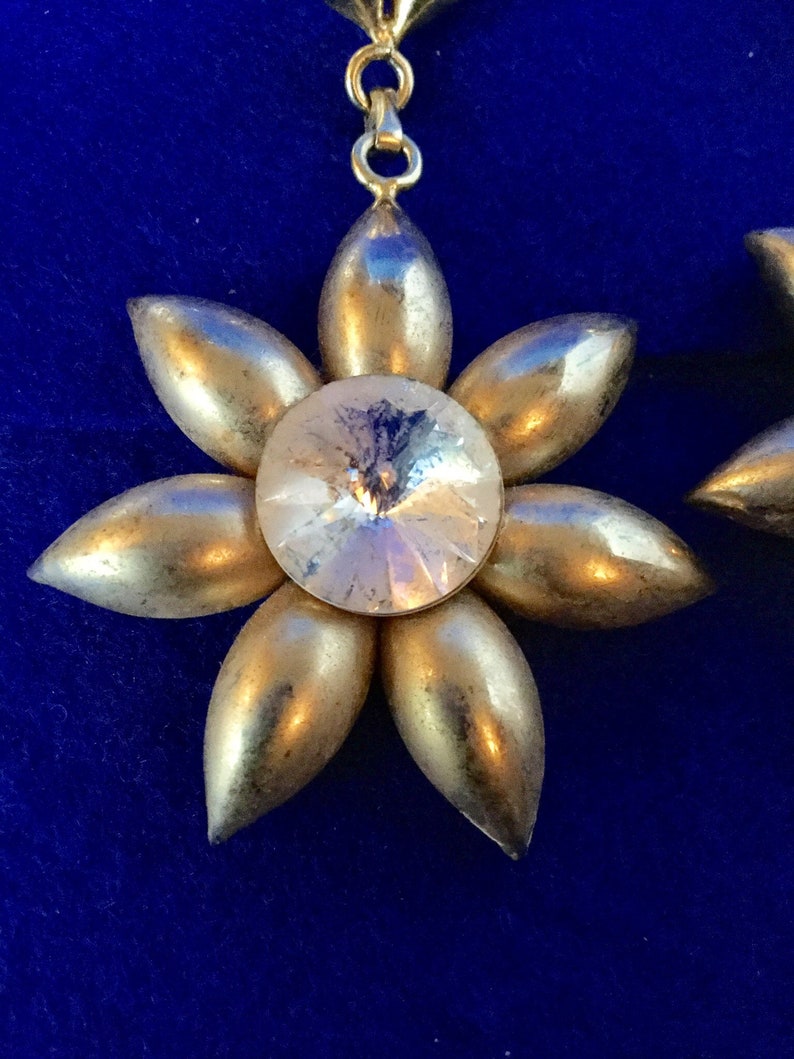 Vintage 1970s chandelier drop earrings in gold toned metal with dramatic plastic faux rhinestone centres.