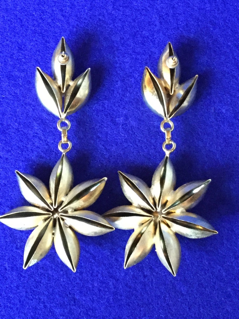 Vintage 1970s chandelier drop earrings in gold toned metal with dramatic plastic faux rhinestone centres.