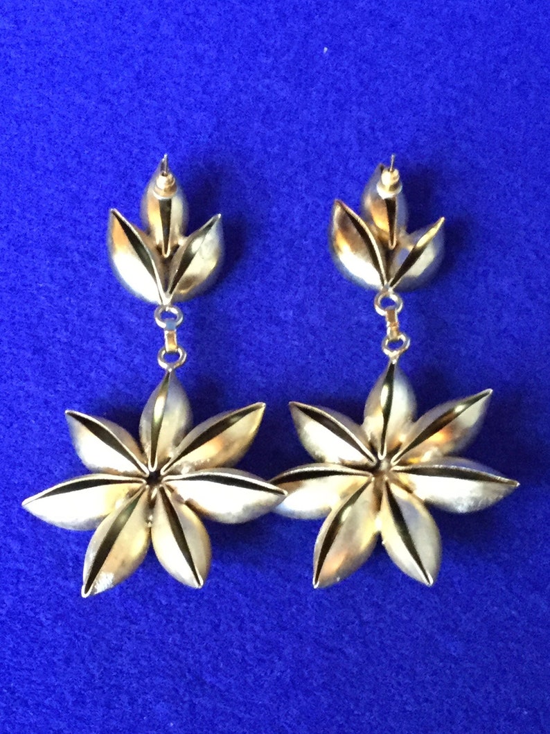 Vintage 1970s chandelier drop earrings in gold toned metal with dramatic plastic faux rhinestone centres.