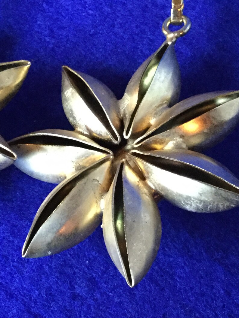 Vintage 1970s chandelier drop earrings in gold toned metal with dramatic plastic faux rhinestone centres.