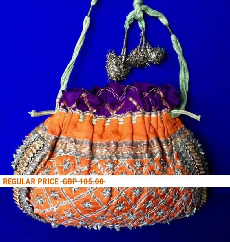 May include: A small, orange and purple drawstring bag with silver and gold embroidery. The bag has a beaded fringe and a green cord handle. "REGULAR PRICE - GBP 105.00" is printed on a white banner.