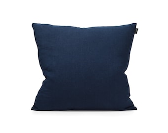 May include: A square, navy blue decorative pillow. The pillow has a textured fabric and a tag on the side. The pillow is a solid color and is set against a white background. This pillow is suitable for home decor.
